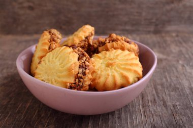 Yoğunlaştırılmış süt ve eski ahşap arka planda bir tabakta fındıklı sandviç kurabiyeleri..