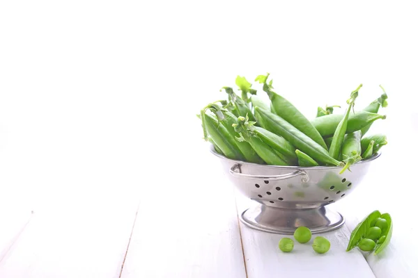 Young green peas in a metal colander — Stock Photo, Image