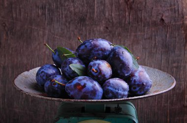 Karanlık bir arka plan üzerinde metal bir kabın içinde mor Erik