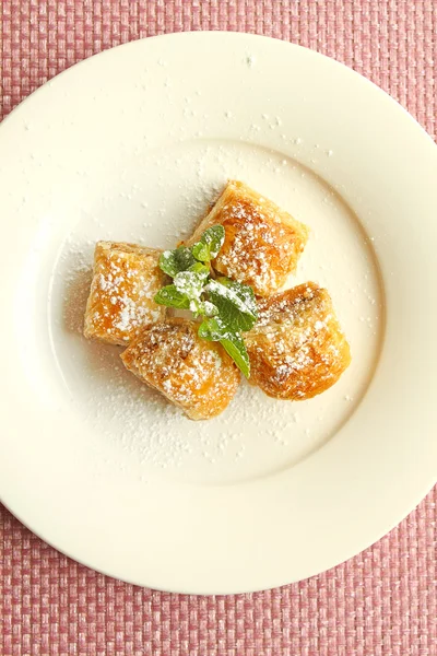 Восточные сладости: пахлава с грецкими орехами на тарелке с мятой и сахарной пудрой — стоковое фото