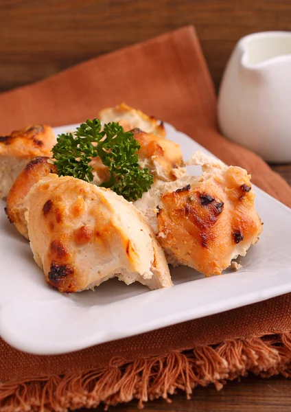 Цыпленок, запеченный со специями в белой тарелке на темном фоне — стоковое фото
