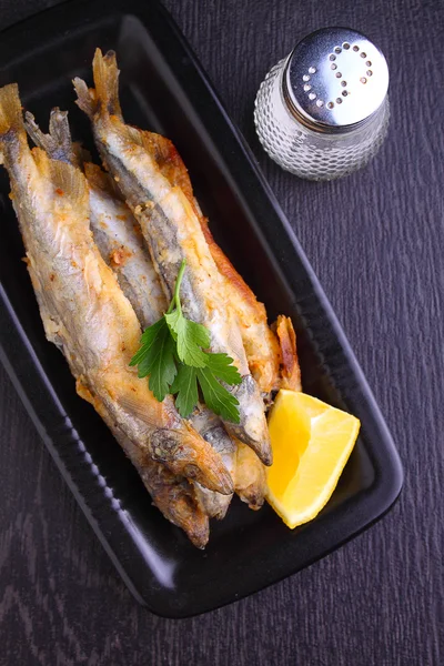 Жареная рыба "capelin" в черной табличке на черном фоне — стоковое фото
