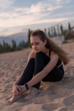 Gün batımında sahilde jimnastik, yoga, meditasyon ve ayrılık eğitimi alan genç bir kız. Konsept - gençler için egzersiz ve sağlık hizmetleri hakkında.