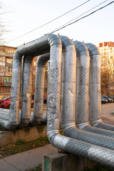 Bending of metal pipes of the city heating system lkx for pedestrian walkways along the path in the courtyard of a residential building, autumn