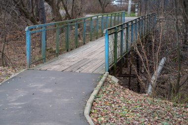 Ahşap döşemeleri ve mavi boyayla kaplı metal korkulukları olan bir vadi üzerindeki köprü.