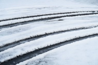 Islak kar, kış ve arka planda araba tekerleği izleri.
