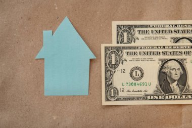 Amerikan banknotlarının arka planında bir evin karton çizgisi, bir ipotek sembolü.