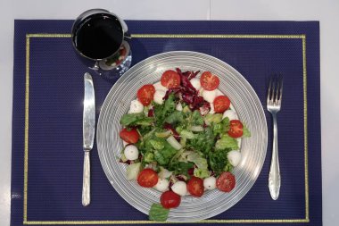 Bir tabak mozzarella ve bir bardak şarap ile vişneli domates salatası