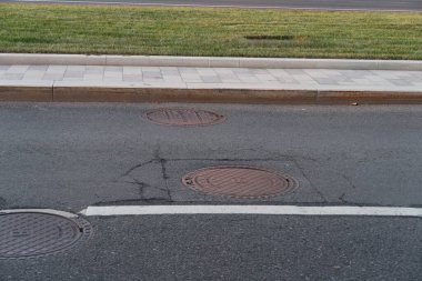 8 Ağustos 2020, Moskova, yoldaki metal rögar kapakları, asfalt, kaldırım, biçilmiş yeşil çimen, minimalizm.