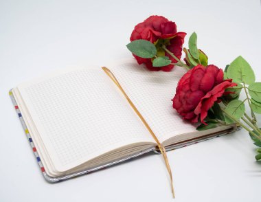 Günlük boş bir sayfada, üzerinde yapay bir gül var.