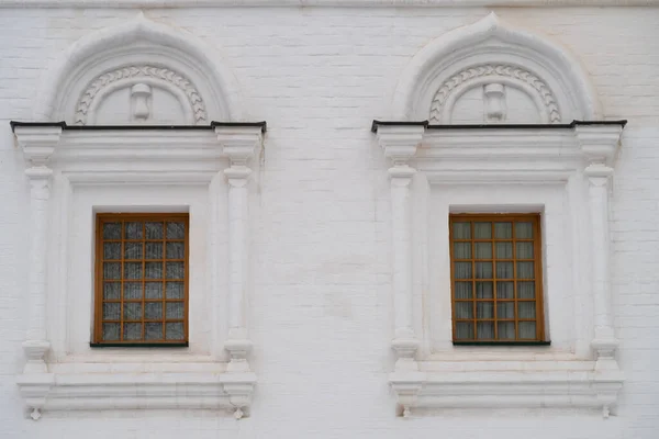 Two arched windows on a white stone wall