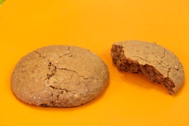 Turuncu arka planda bütün badem kurabiyeleri ve kırık parçalar, tatlılık, zariflik, arka plan