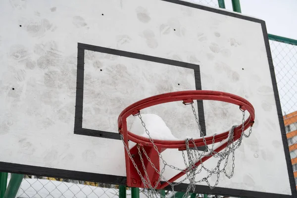 A basketball hoop on a sports ground in a sleeping area covered with snow, Moscow region