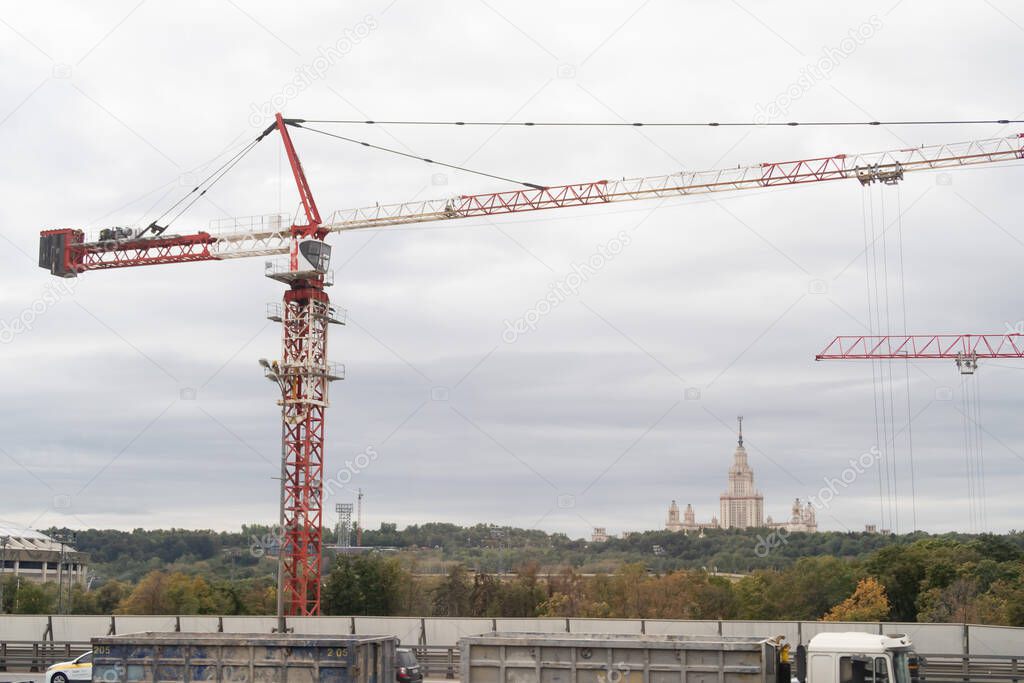 Arrows of construction cranes against the background of green parks and the building of Moscow State University, autumn 2020