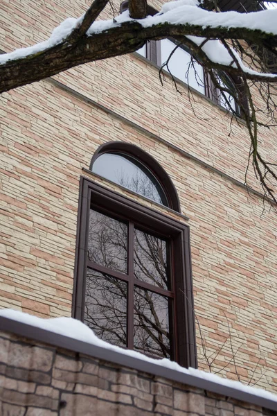 Wysokie Okno Łukowe Ceglanej Ścianie Odbiciem Gołych Gałęzi Śniegiem Drzewach — Zdjęcie stockowe