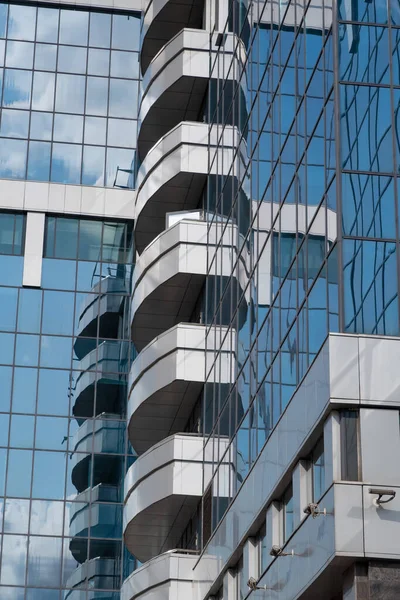 Balconies and blue sky reflected in glass wall of high-rise building, glass background, Moscow