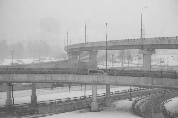 Cityscape during heavy snowfall, busy highway with challenging overpass
