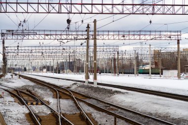Tren istasyonunda demiryolu rayları, teller ve metal yapılar var.