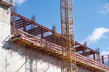 İnşaat vincinin sopası yakınındaki beton bir duvarda inşaat ve inşaat demiri. 2021 'de büyük bir bina inşa edilmiş.