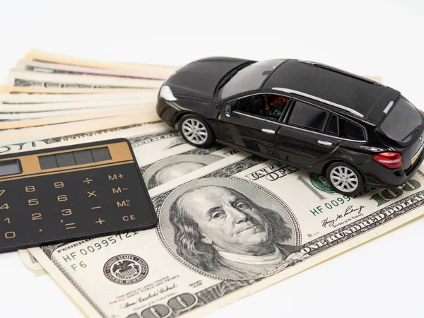 Toy car and calculator lie on american banknotes, mortgage and car insurance