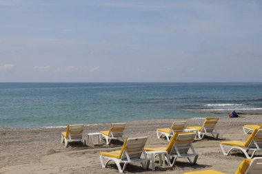 Denizin ve dalgaların arka planında kumlu bir kumsalda boş güneşlenme yerleri, plaj sezonu için hazırlık, ruh hali, deniz arka planı, Alanya, Nisan 2021