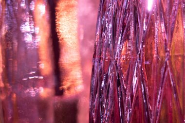 Işığın parlaklığında sevilen bir yüzeye sahip cam vazo, değişmiş renkte parlak arkaplan.