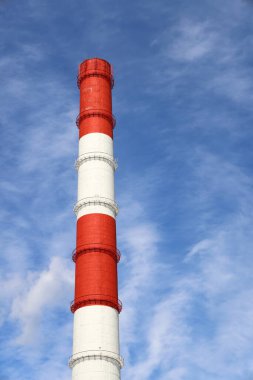Mavi gökyüzüne karşı bir ısıtma istasyonunun yüksek kırmızı ve beyaz bacası, arka plan