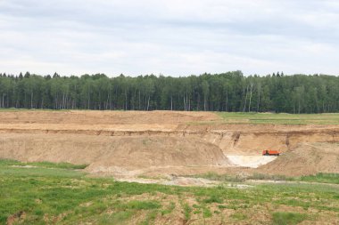 Moskova bölgesindeki yeşil bir ormanın arka planında eski çimenli bir taş ocağı, Haziran 2021