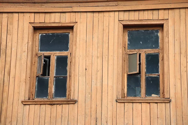 Two windows with wooden frames in a wooden plank wall, wooden background