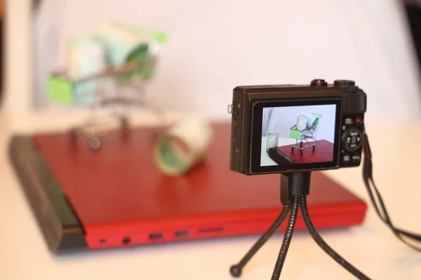 三脚の上のカメラは ノートパソコンの蓋に紙幣が付いているおもちゃのカートの写真 写真のセッション 写真の株式のための写真 — ストック写真