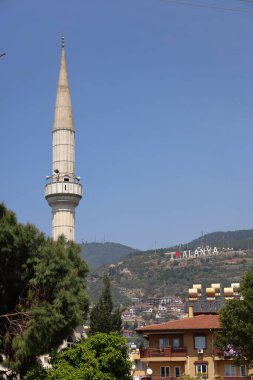 Yeşil dağların arka planına karşı yüksek minare ve Alanya, Nisan 2021
