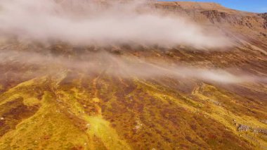 Bulutlar ve sisli bir fiyortta manzaranın havadan görüntüsü İzlanda