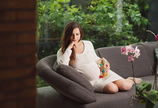 Hermosa mujer embarazada sentada en el sofá —  Fotos de Stock
