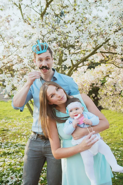 Šťastná rodina s roztomilé dcerušky v květu stromů — Stock fotografie
