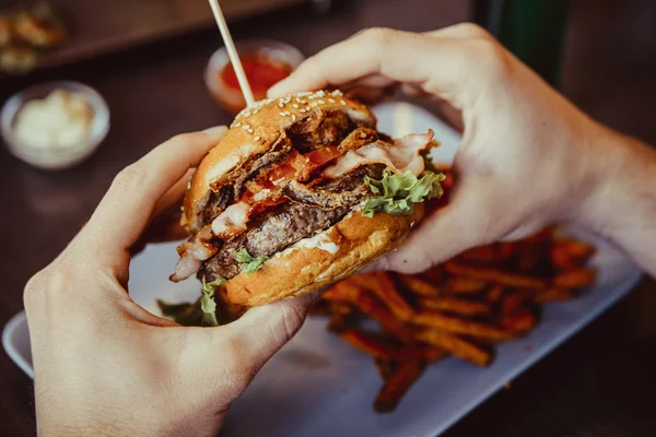 adam burger eller ve tatlı patates kızartması tutar ve üzerinde dips 