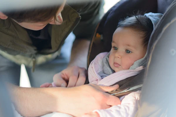 Vater setzt seine kleine Tochter in den Autositz im Auto — Stockfoto