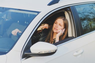 Bir araba sürüş sırasında cep telefonu kullanan genç kadın