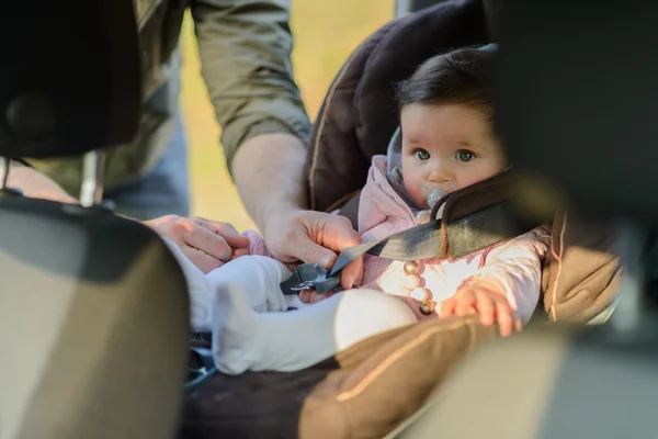 Een vader zijn dochter in haar autostoel in de auto brengen — Stockfoto