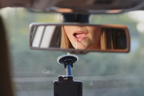 Young woman using lipgloss in car — Stock Photo, Image