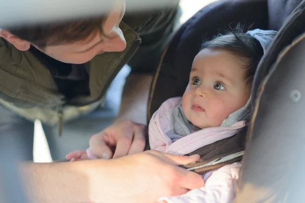 Un père mettant sa petite fille dans son siège auto dans la voiture — Photo