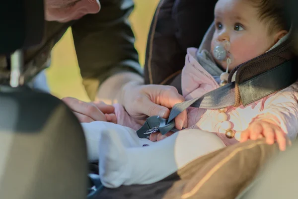 A father putting his baby daughter into her car seat in the car — Stock Photo, Image