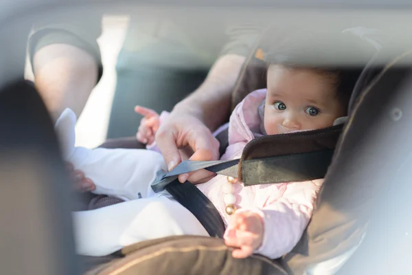 Un padre che mette sua figlia nel suo seggiolino in macchina — Foto Stock