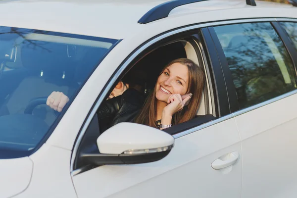 Jonge vrouw met behulp van mobiele telefoon tijdens het rijden van een auto — Stockfoto