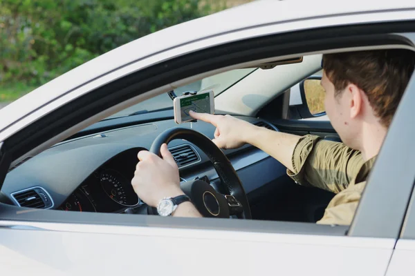 Handsome man in car points at navigation — Stock Photo, Image