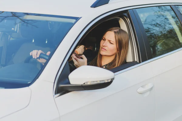 Jonge vrouw met behulp van mobiele telefoon tijdens het rijden van een auto — Stockfoto