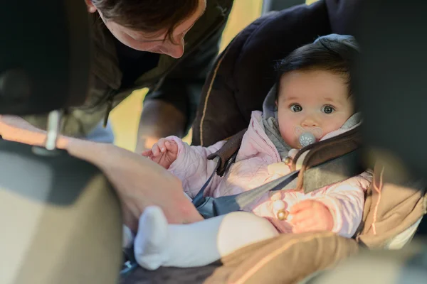 A father putting his baby daughter into her car seat in the car — Stock Photo, Image