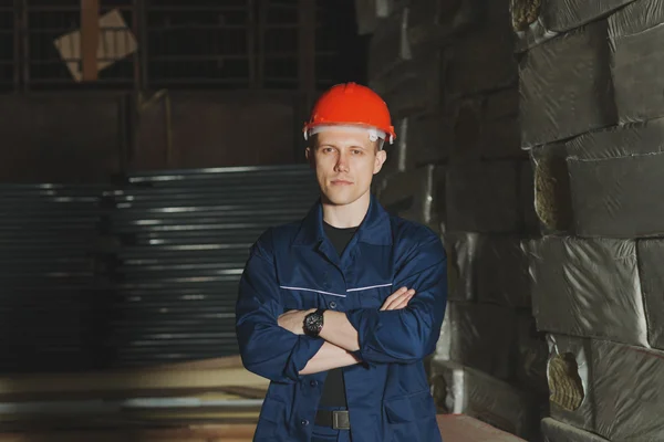 Trabajador en una gorra roja y uniforme se levanta contra el telón de fondo de t — Foto de Stock