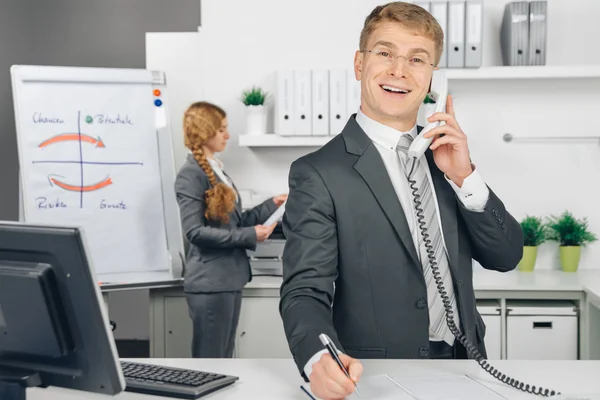 Attraktiv business man speaking at telephone in office — Stock Photo, Image