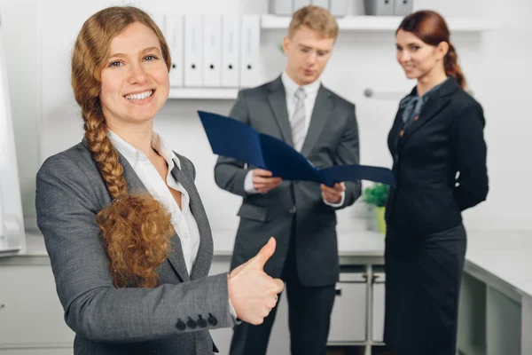 Business woman working in office shows thumb up — Stock Photo, Image