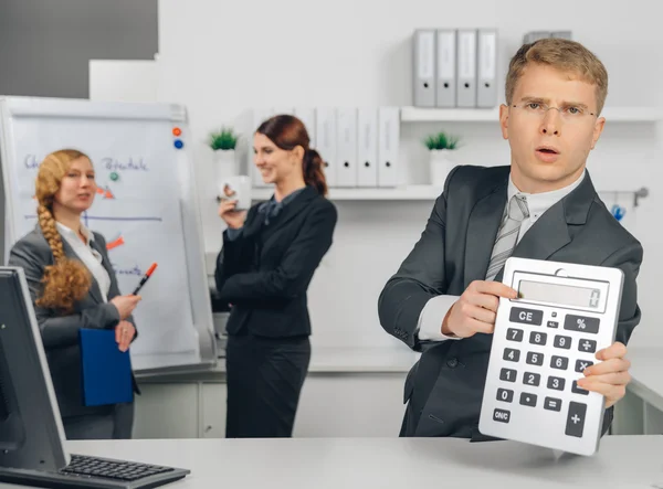 Handsome businessman calculating at calculator — Stock Photo, Image